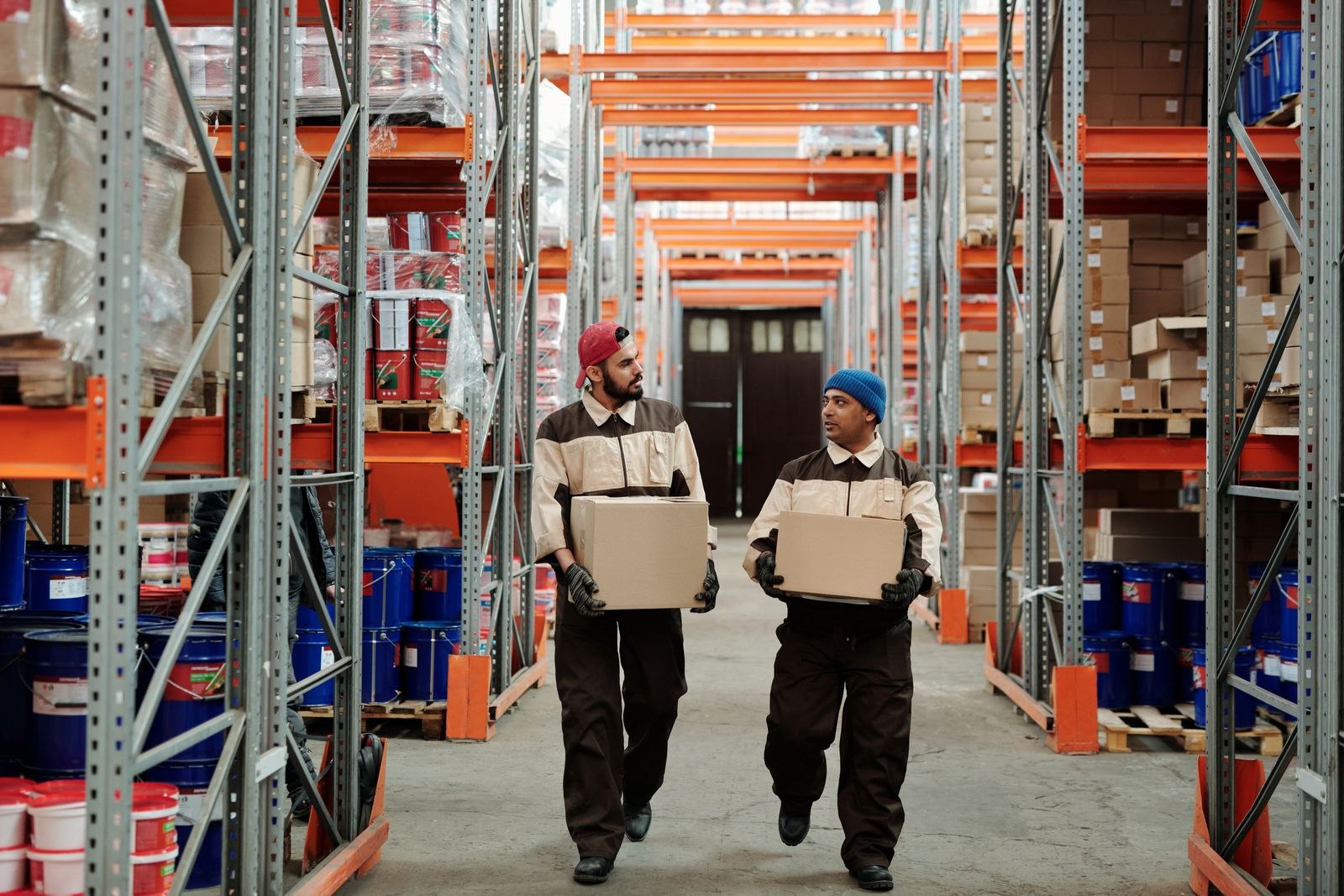 Warehouse worker carrying a carton among stocked shelves