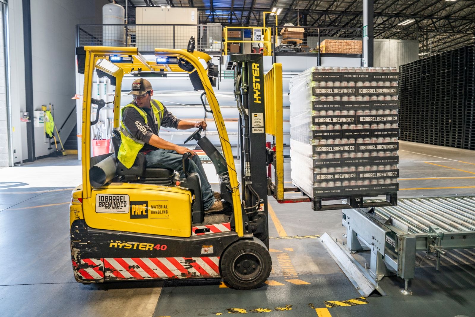 Forklift operator moving palletized goods inside a warehouse
