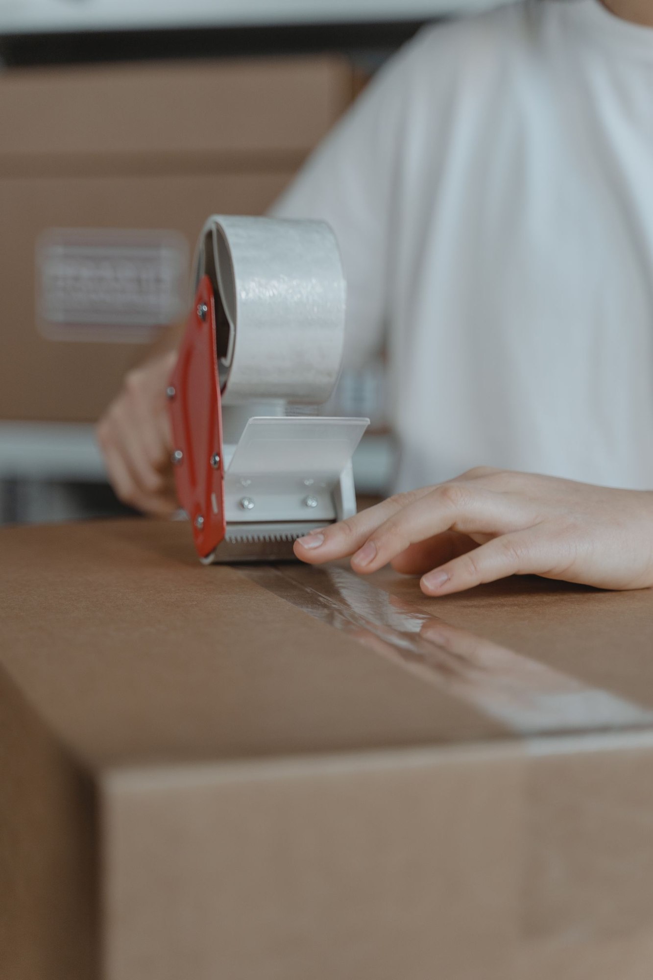 Hands sealing a cardboard carton with packing tape